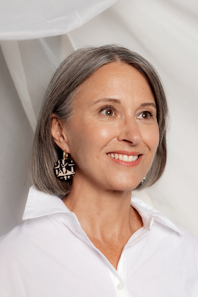 Mustat Sinua Forever Classic -puukorvakorut kultaisilla korvarenkailla, mallin päällä.