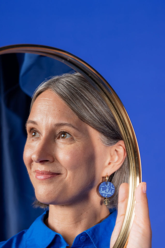 Siniset Sinua Forever Dreaming -puukorvakorut logoriipuksella ja kultaisilla korvarenkailla, mallin päällä.