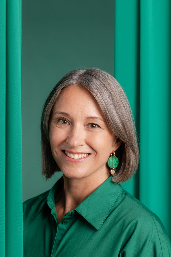 Vihreät Sinua Forever Growing puukorvakorut logoriipuksella ja kultaislla korvarenkailla, mallin päällä