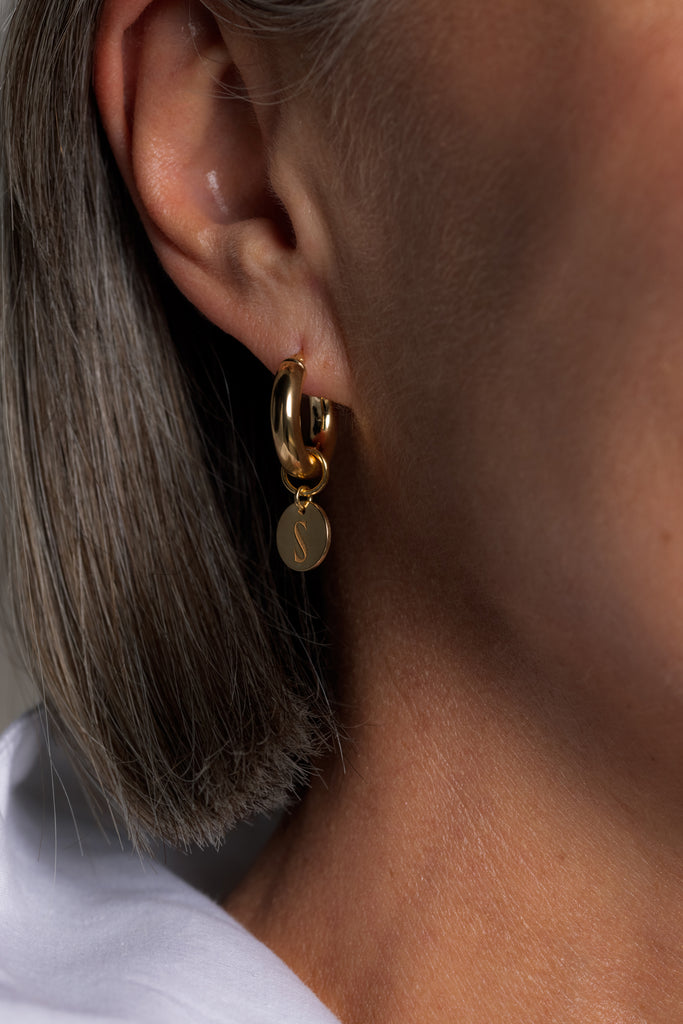 Kultaiset Sinua Forever korvarenkaat logoriipuksella, lähikuva mallin päällä